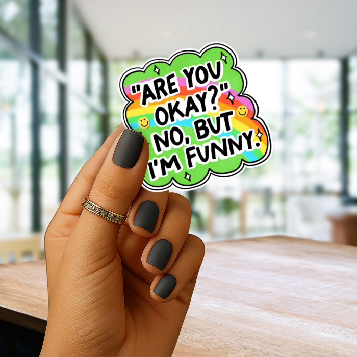 Hand holding a colorful sticker with Are you okay and emojis in an indoor setting