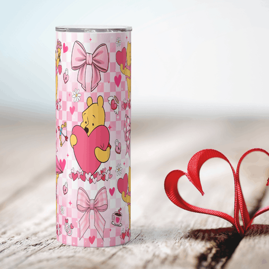 Pink tumbler with cartoon character holding a heart on a light wooden surface.