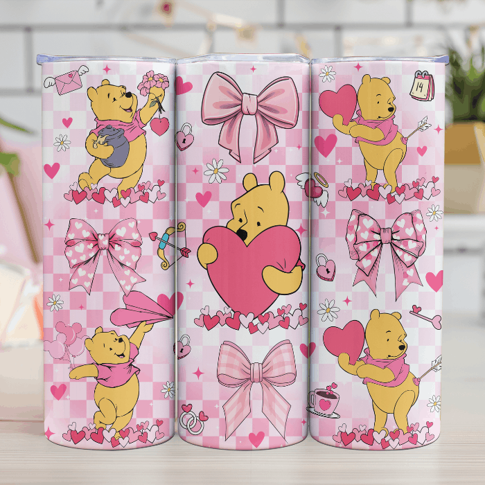 Three pink tumblers with cartoon bear designs and hearts on a checkered background.