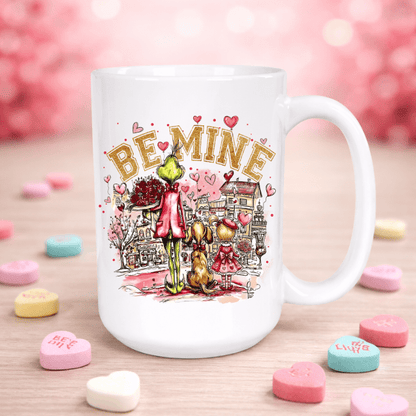 White mug with 'Be Mine' design featuring cartoon characters on a pink background with heart-shaped candies.