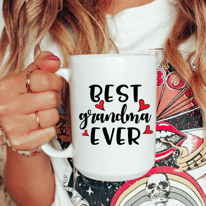 Person holding a white mug with 'Best Grandma Ever' text
