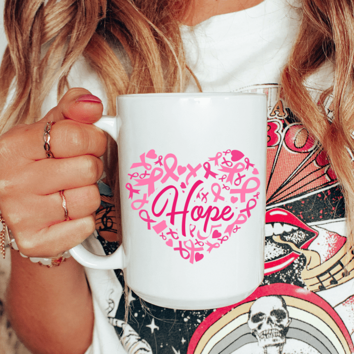 White mug with pink 'Hope' design held by a person with a colorful background
