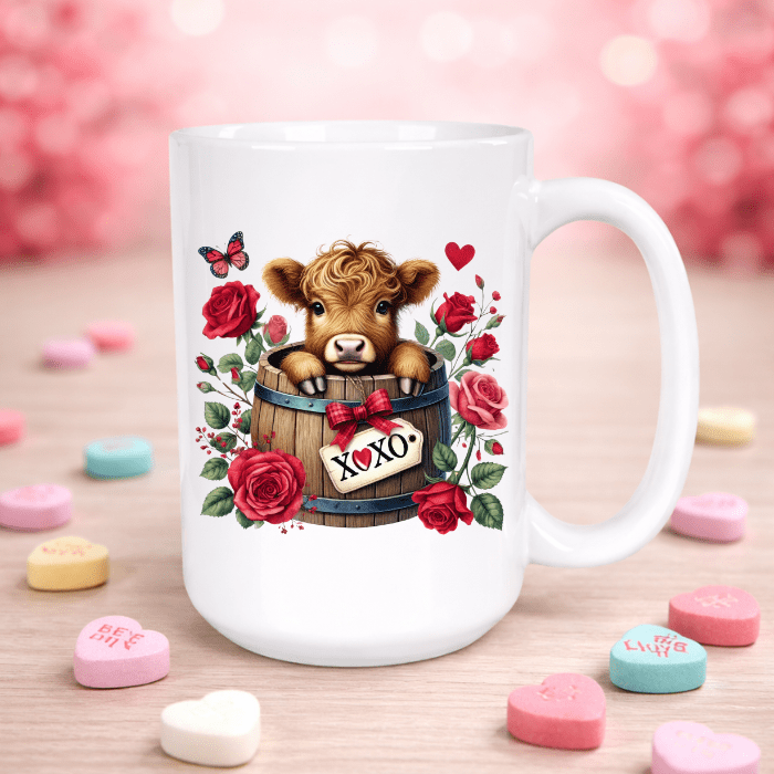 Mug with a cow design in a barrel surrounded by roses and hearts on a pink background with candy hearts.