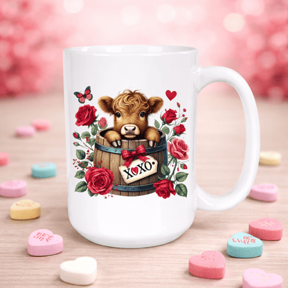Mug with a cow design in a barrel surrounded by roses and hearts on a pink background with candy hearts.