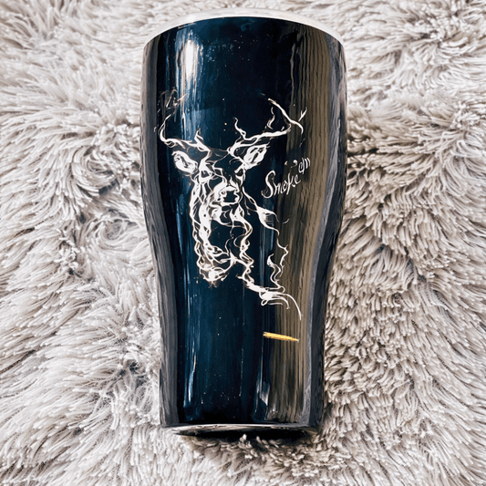 Black tumbler with white deer design on a fluffy beige surface