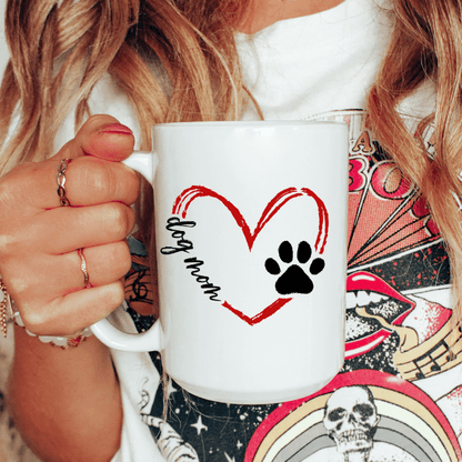 Person holding a white mug with a heart and paw print design, text 'dog mom'.