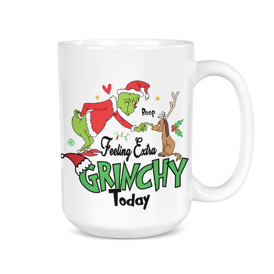 White mug with Grinch and reindeer design and text 'Feeling Extra Grinchy Today' on a white background