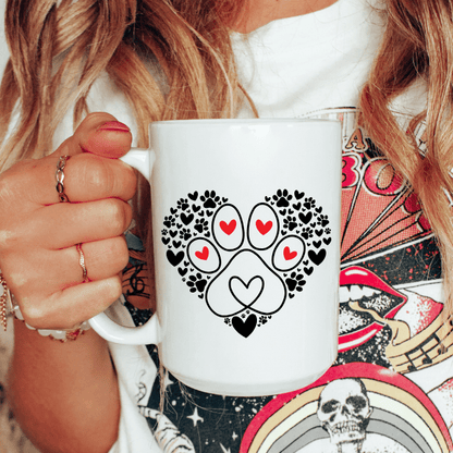 Person holding a white mug with a paw print design featuring hearts.