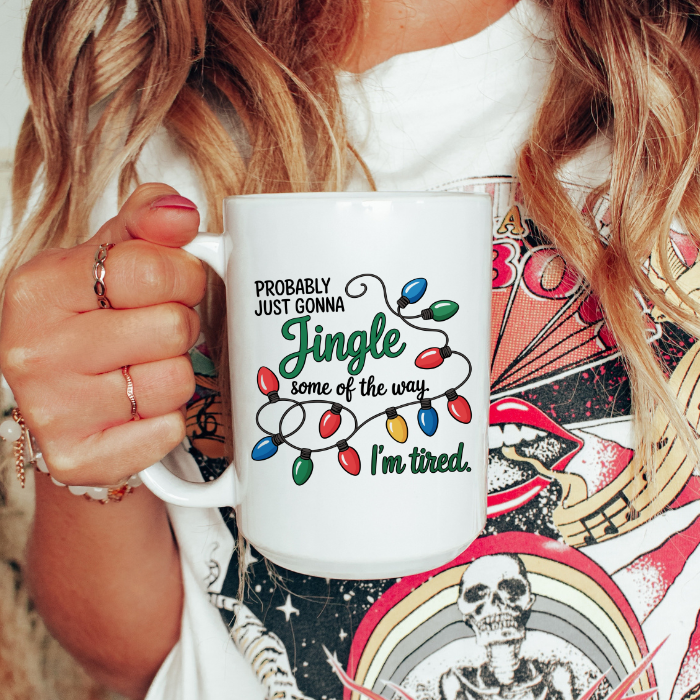 Person holding a white mug with a Christmas-themed design and text.