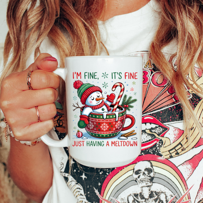 Person holding a mug with a Christmas-themed design featuring a snowman and text.