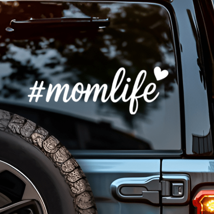 Car window with '#momlife' decal and heart symbols
