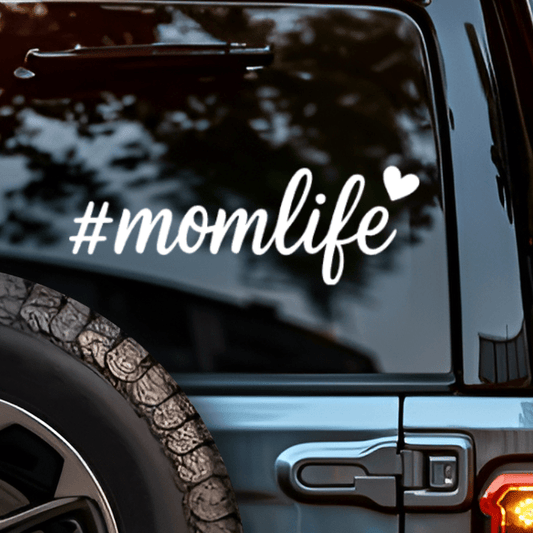 Car window with '#momlife' decal and heart symbols