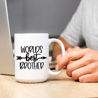 White mug with 'Worlds Best Brother' text held by a person at a desk.