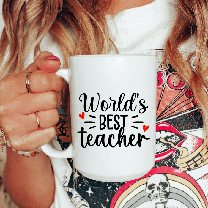 Person holding a white mug with 'World's Best Teacher' text